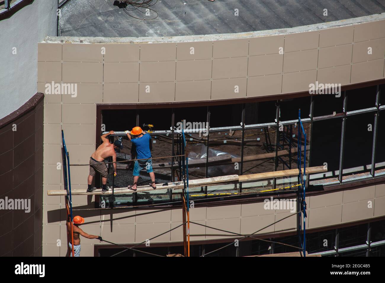 Window workers on a scaffold in construction yard on a building facade Stock Photo