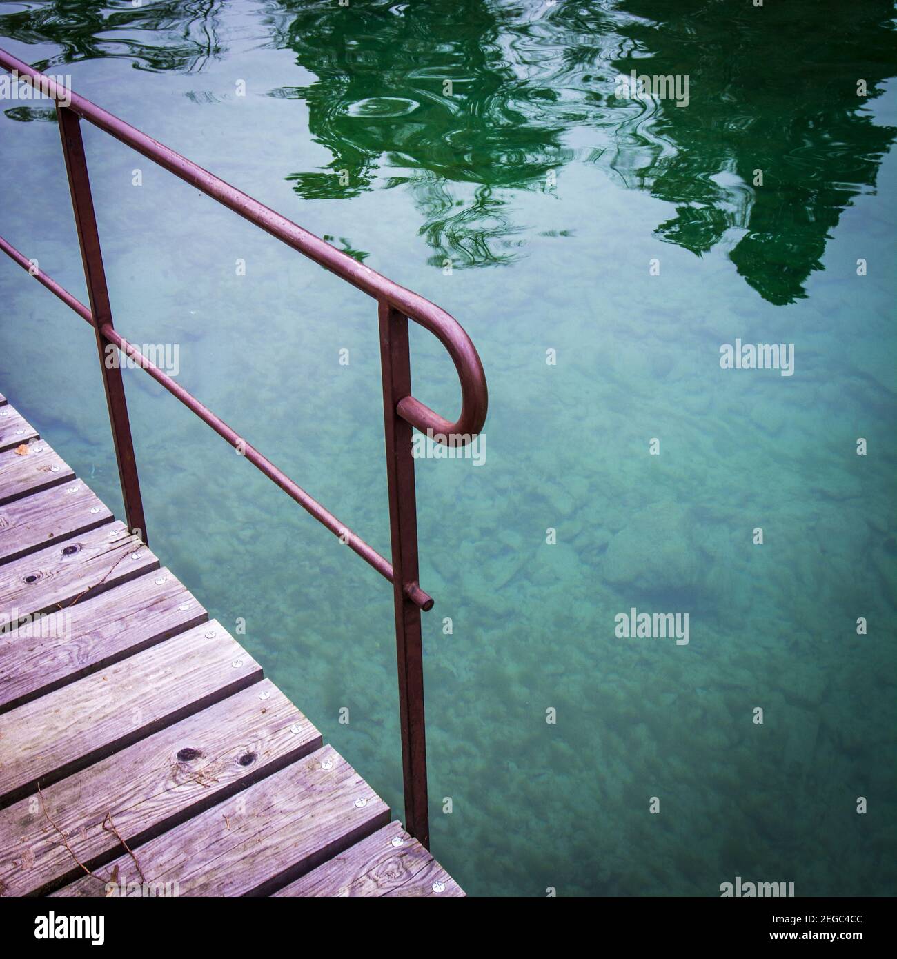 Water Conduction Railing Closeup shot of a red metal railing of a wooden dock and a reflective ...