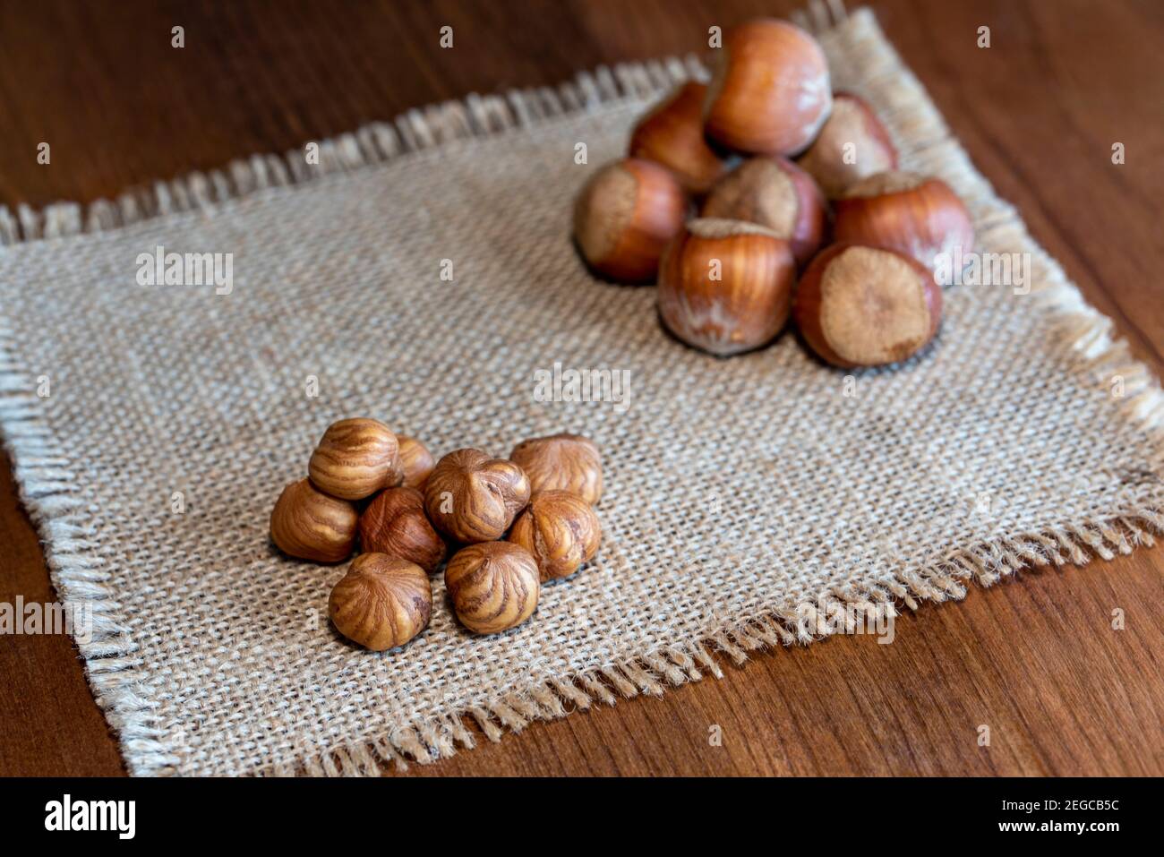 Peeled hazelnuts and hazelnuts in shell on rustic wooden table Stock Photo