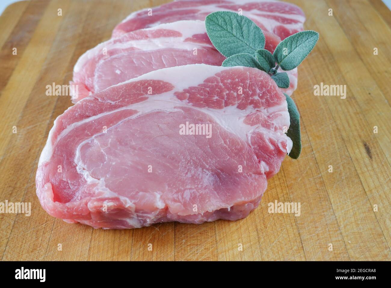 Raw boneless loin Pork chops on a wood kitchen cutting board Stock Photo