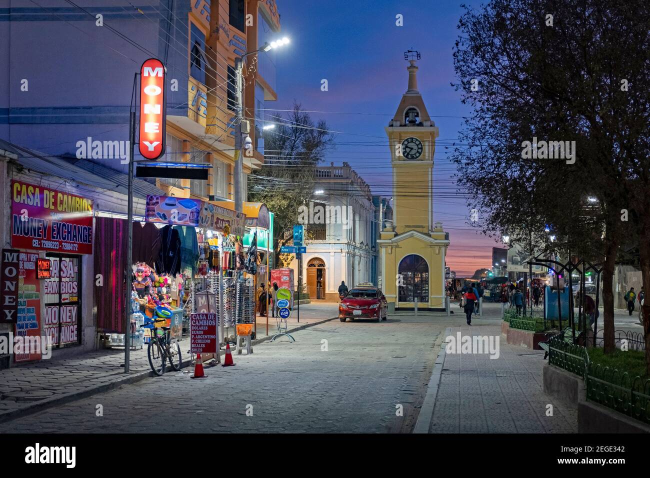 Shops in the main street and yellow clock tower in the city Uyuni after sunset, Antonio Quijarro Province, Potosí Department, Bolivia Stock Photo