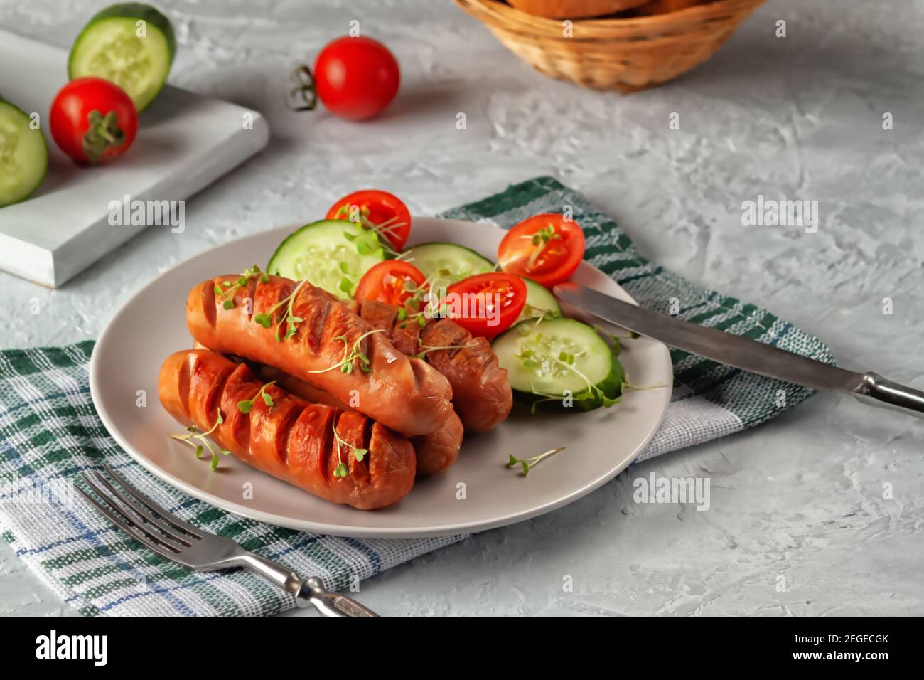 Grilled sausages with fresh vegetables are on the platter Stock Photo