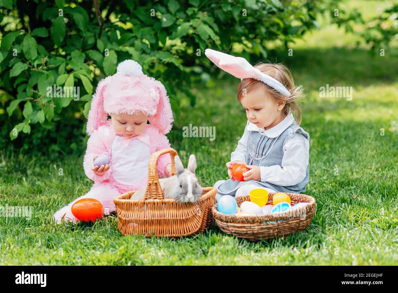 Children play with real rabbit. Laughing child at Easter egg hunt with