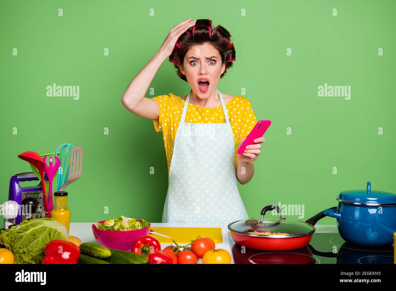 Woman in hair curlers taking funny selfie on mobile while cooking in the  kitchen Stock Photo - Alamy