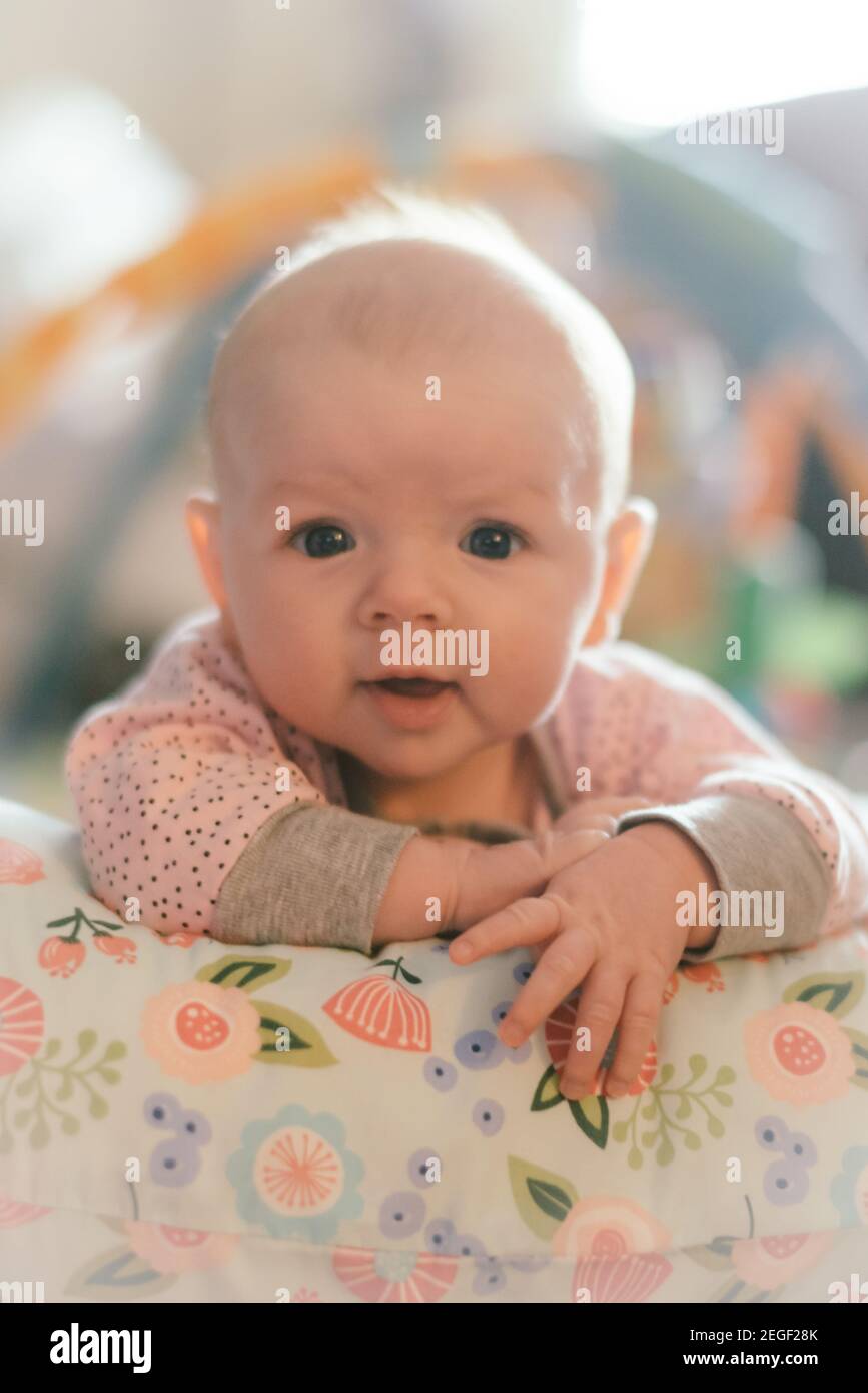 Three month old baby girl holding herself up on a pillow Stock Photo