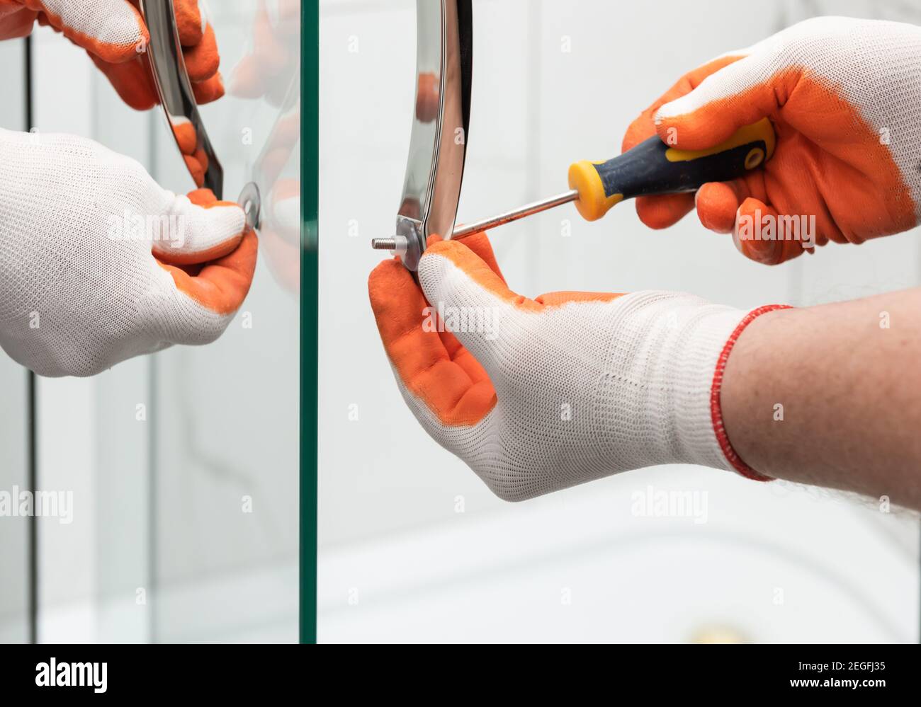 Workers are mounting door handles of the shower enclosure Stock Photo