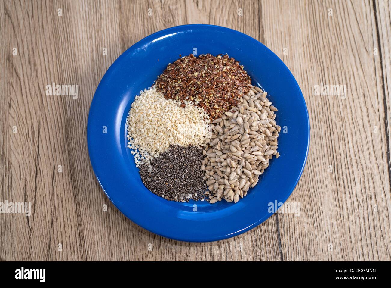 Topdown photo of the plate with different seeds - chia, sunflower seeds, sezame and flax or linseed. Health eating. Stock Photo