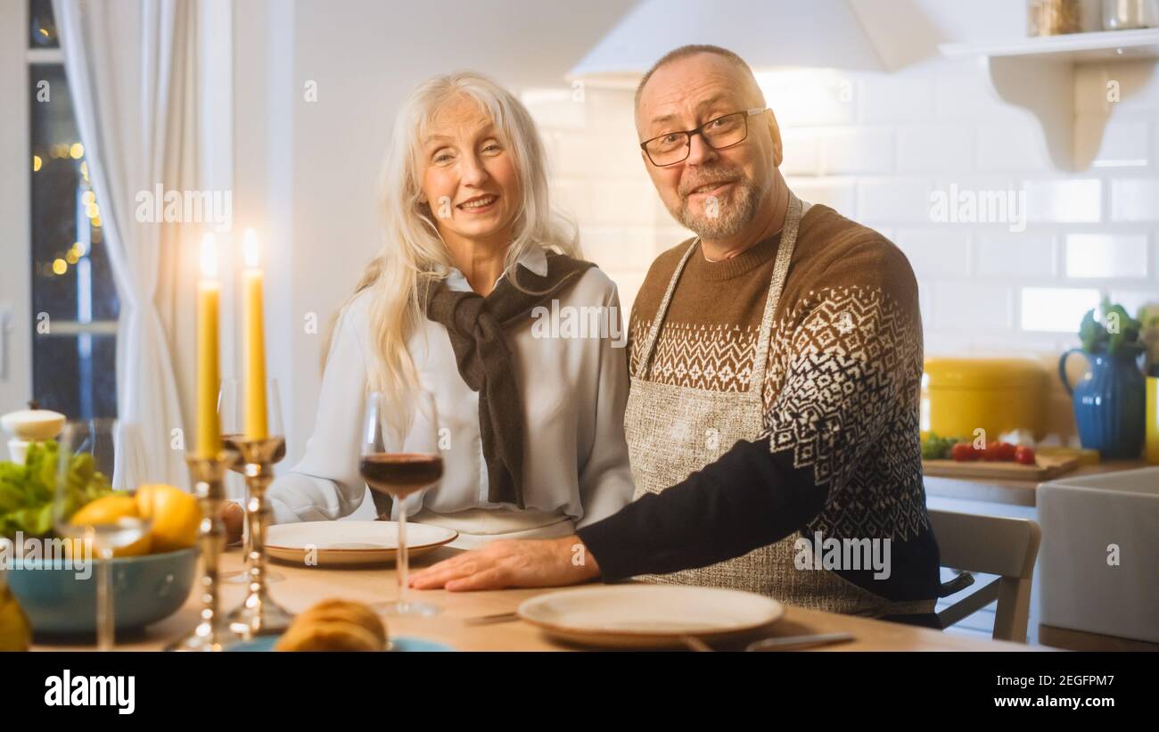 Happy Senior Couple in Love Have Romantic Evening, Smiling on Camera and Celebrating Anniversary. Elderly Have Romantic Evening with Wine, Festive Stock Photo