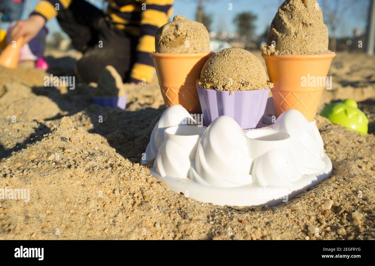 Child making delicious sand ice cream. Sunny afternoon light. Selective focus Stock Photo