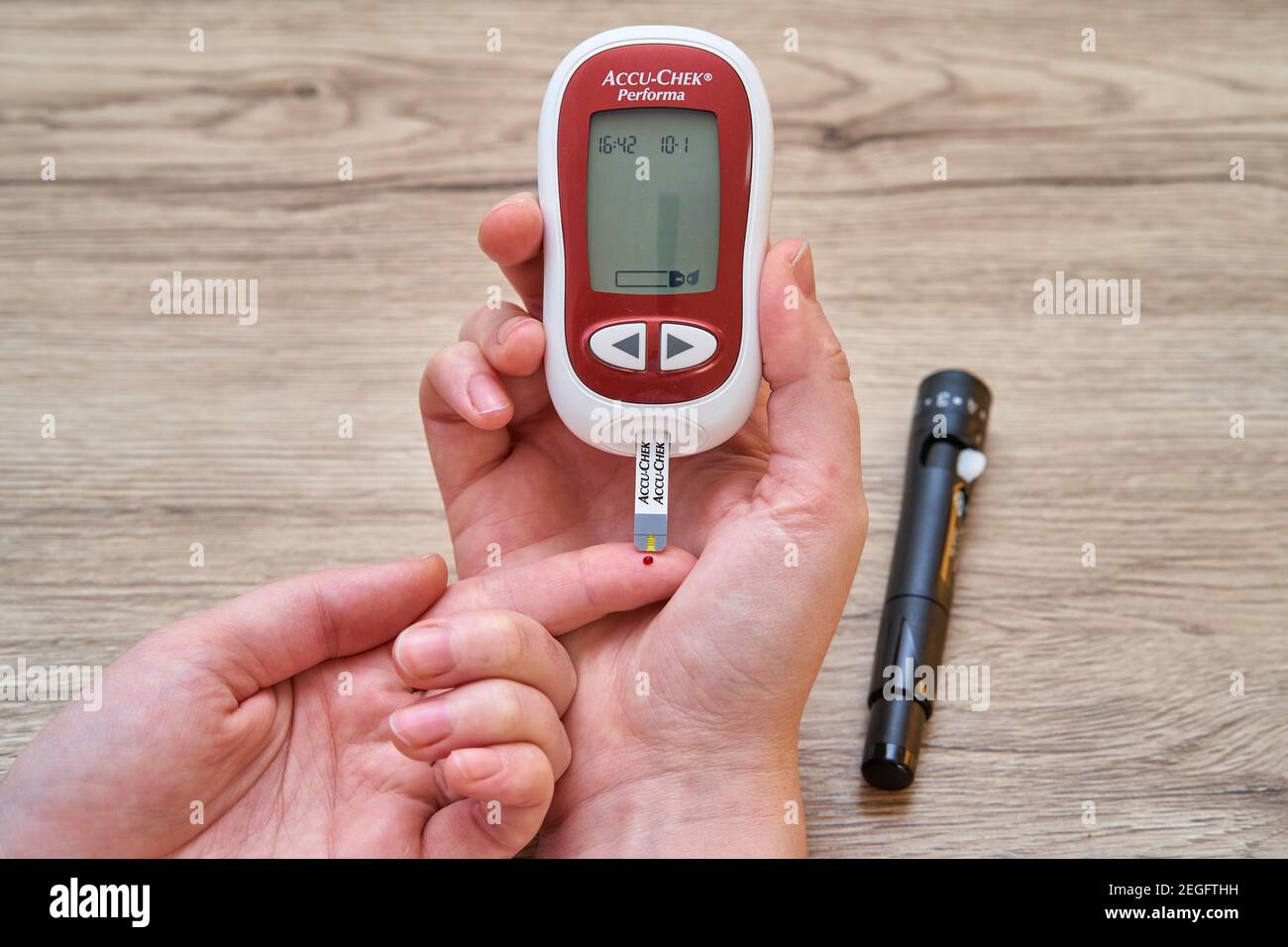Measuring blood sugar with glucometer at home. A drop of blood on the fingertip and test strip. Stock Photo