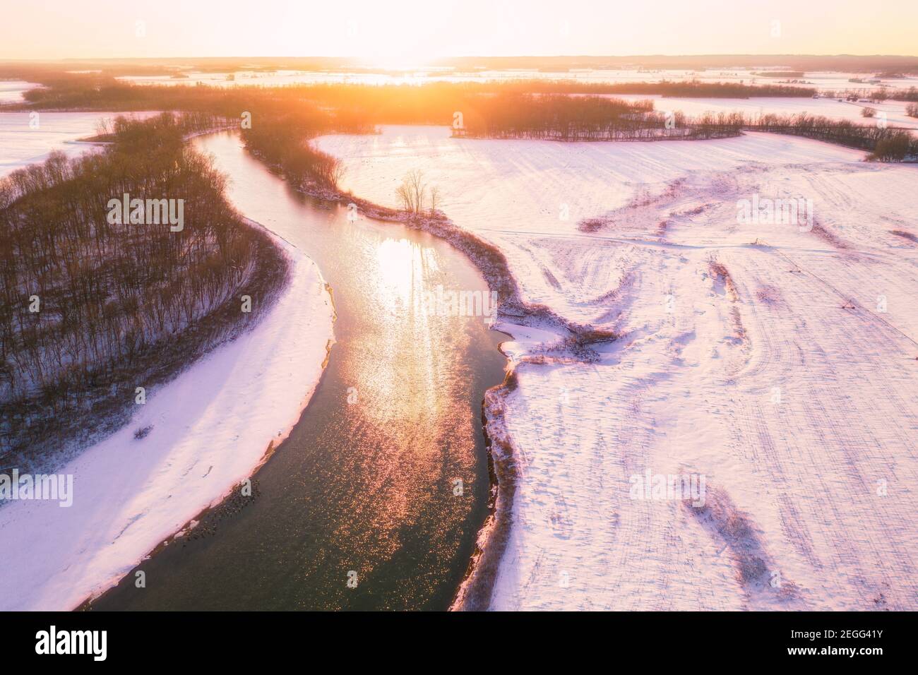 A sunset scene over the white river in Jackson County, IN.  The snow has a magenta hue and several flocks of sandhill cranes are on the river and air. Stock Photo