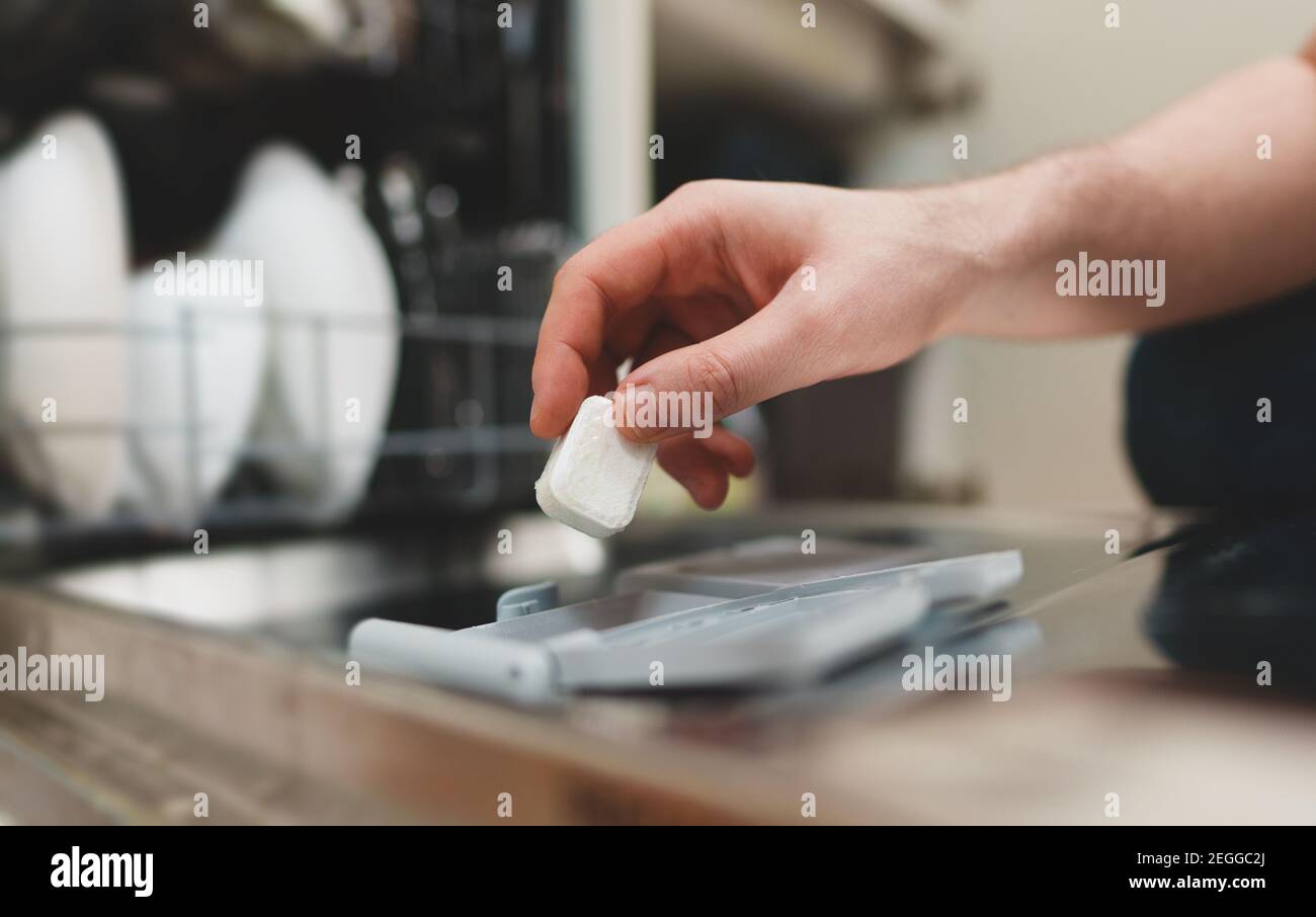 Man putting detergent tablet into dishwasher Stock Photo Alamy