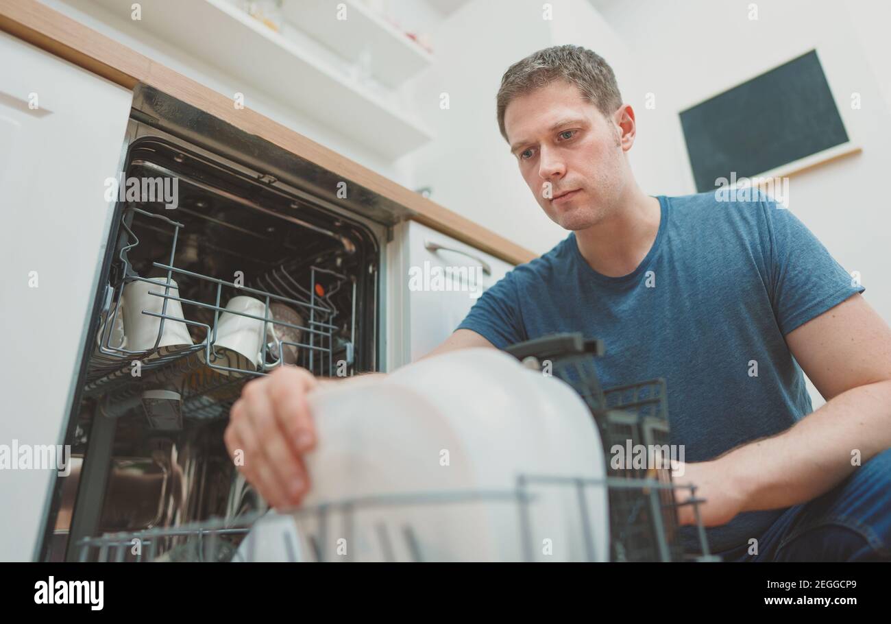 Man puts glass to the dishwasher in the kitchen Stock Photo Alamy