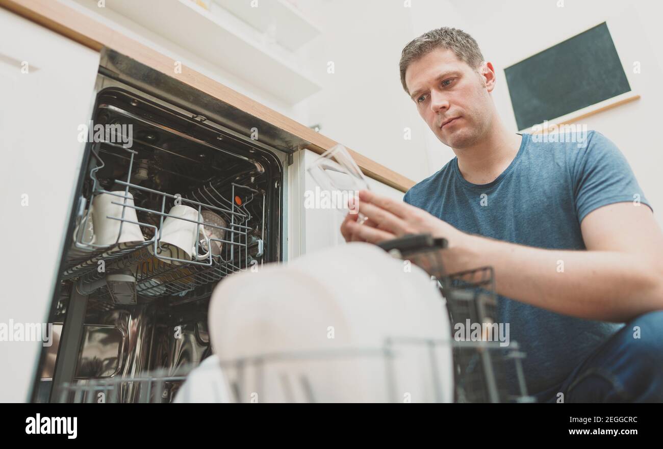 Man puts glass to the dishwasher in the kitchen Stock Photo Alamy