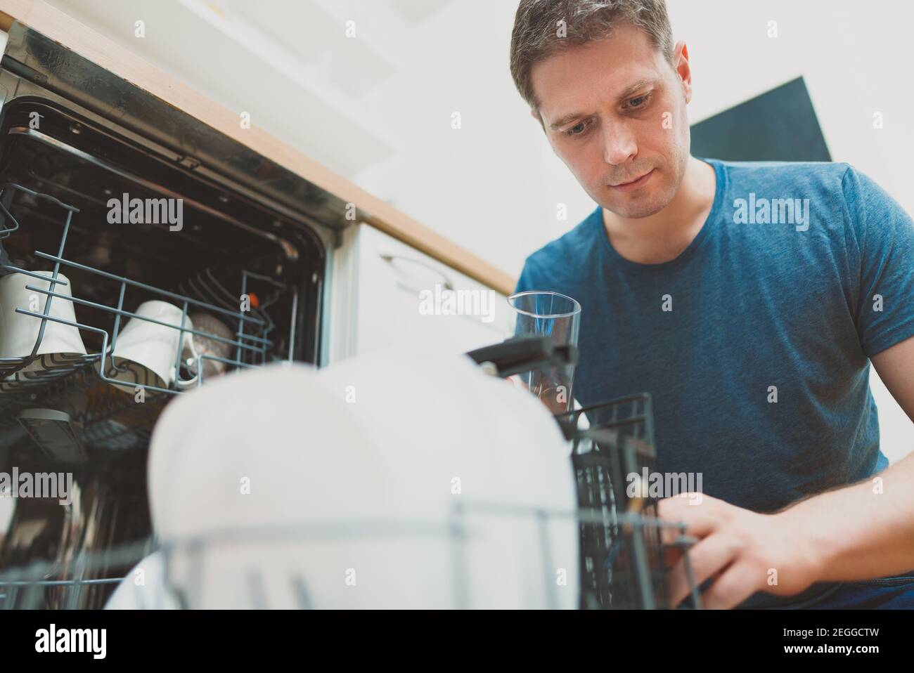 Man puts glass to the dishwasher in the kitchen Stock Photo Alamy