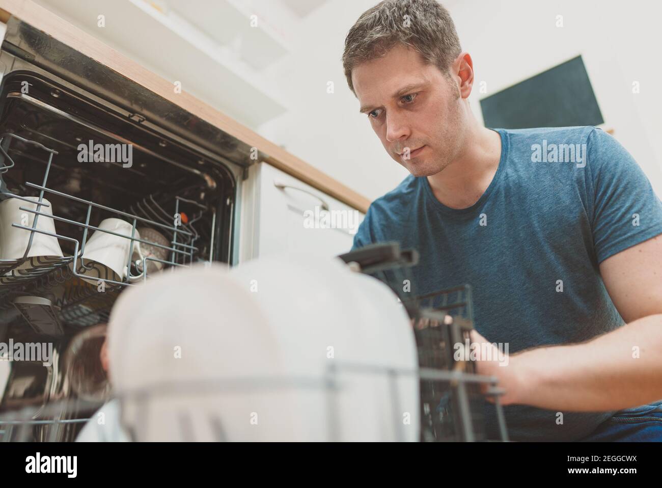 Man puts glass to the dishwasher in the kitchen Stock Photo Alamy