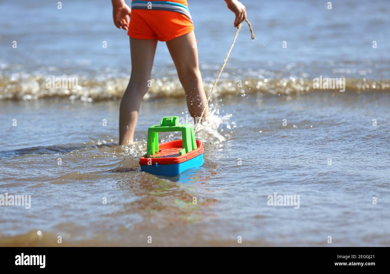 little boy pulling a toy boat into the water Stock Photo Alamy