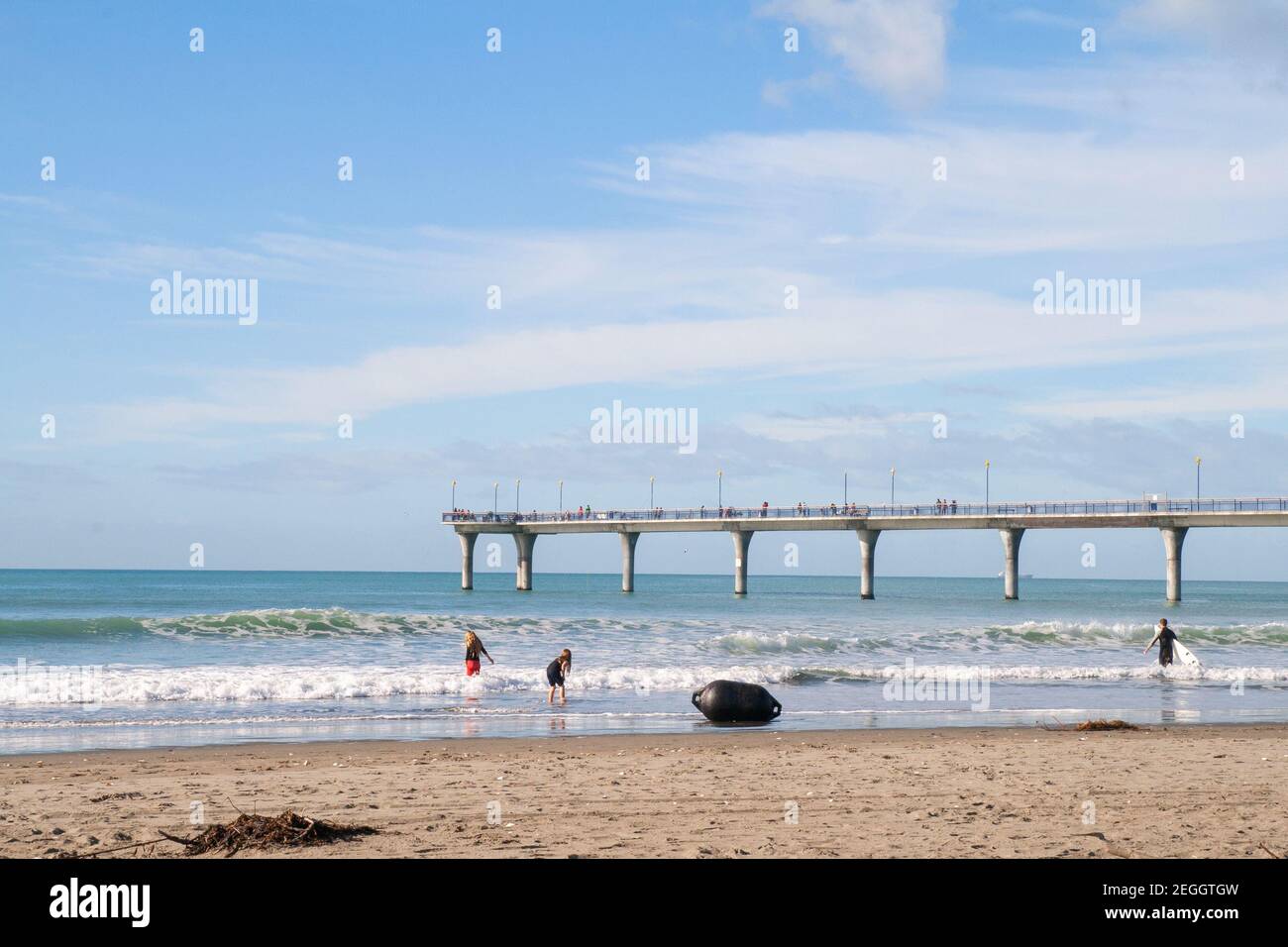 New Brighton Pier, childreen are playing in the waves, Christchurch, South Island New Zealand Stock Photo