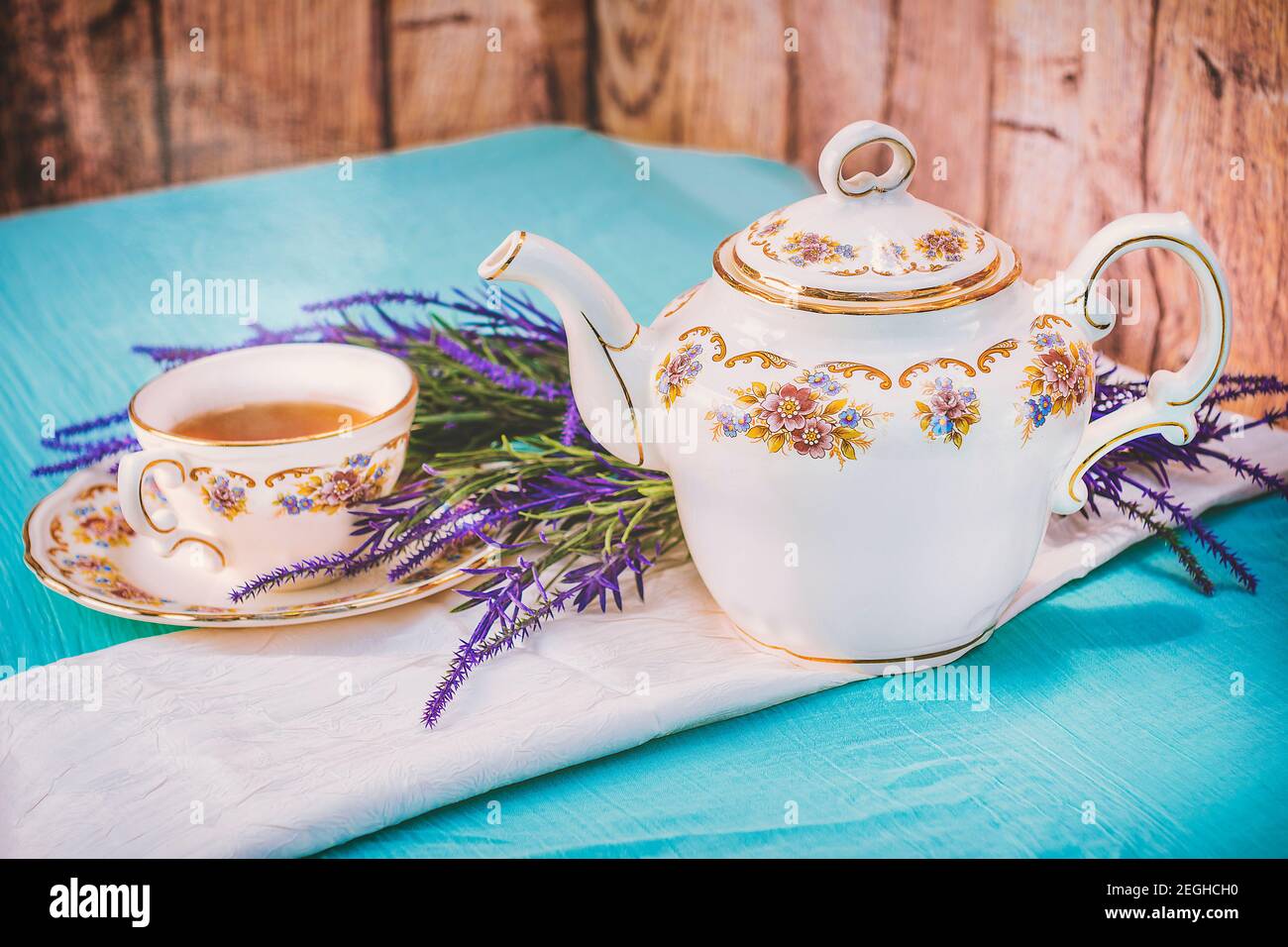 View of a cup of tea and a fine china teapot on a table at sunset Stock Photo
