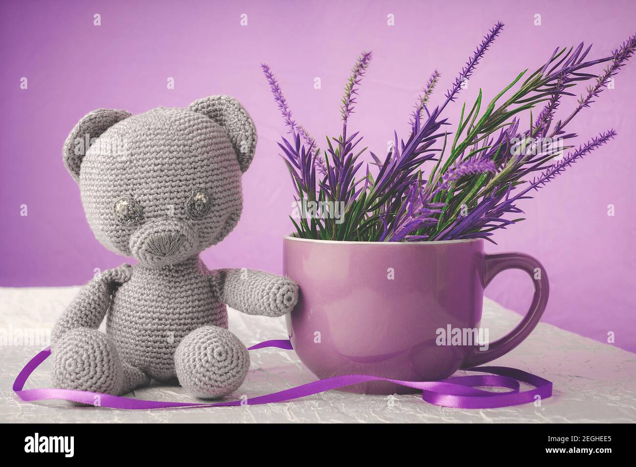 Handmade toy bear of gray color, next to a large mug Stock Photo