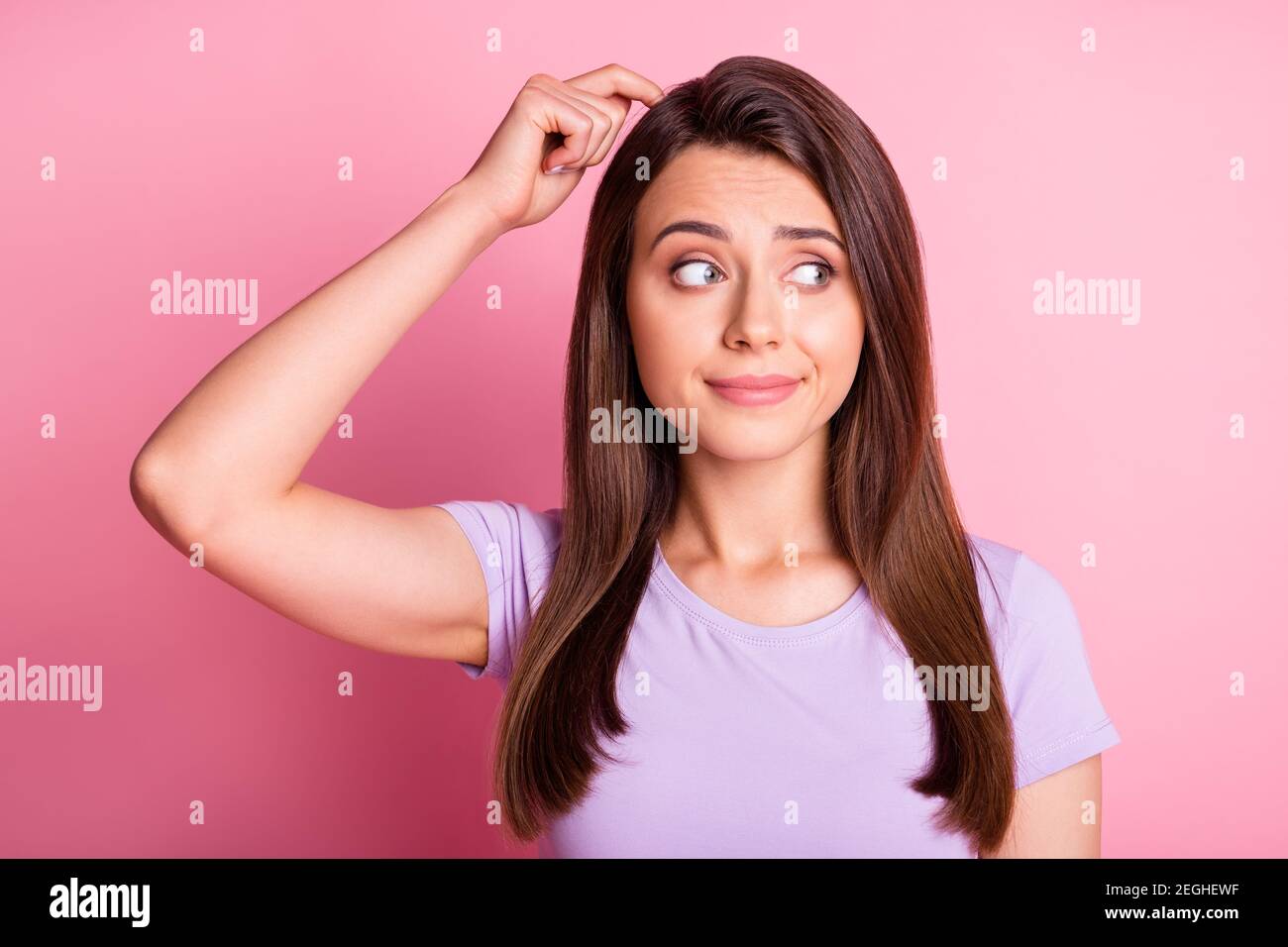 Photo portrait of confused woman scratching head with finger isolated on pastel pink colored background Stock Photo