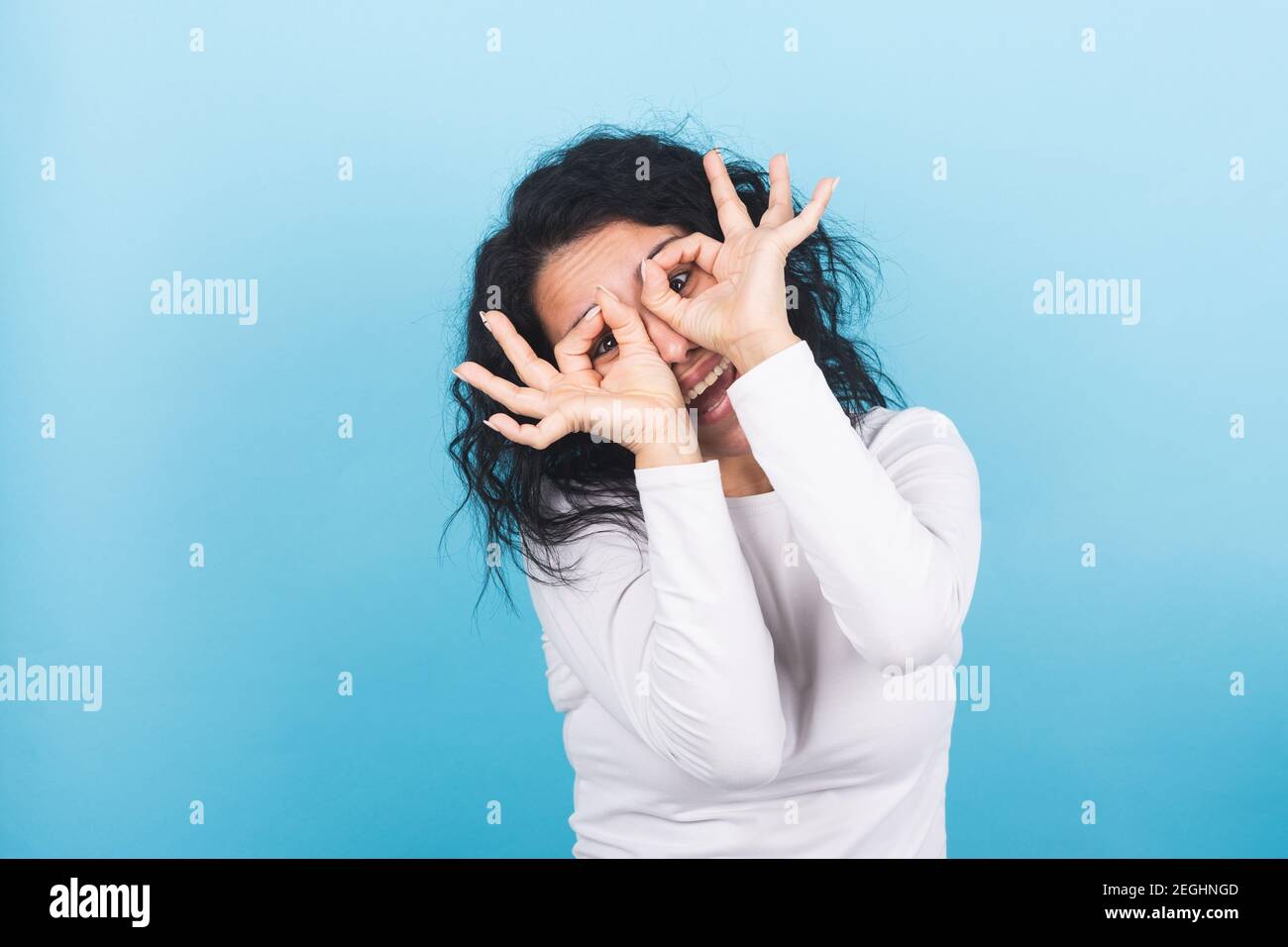 Young brunette woman makes the eyeglasses gesture with her hands Stock Photo