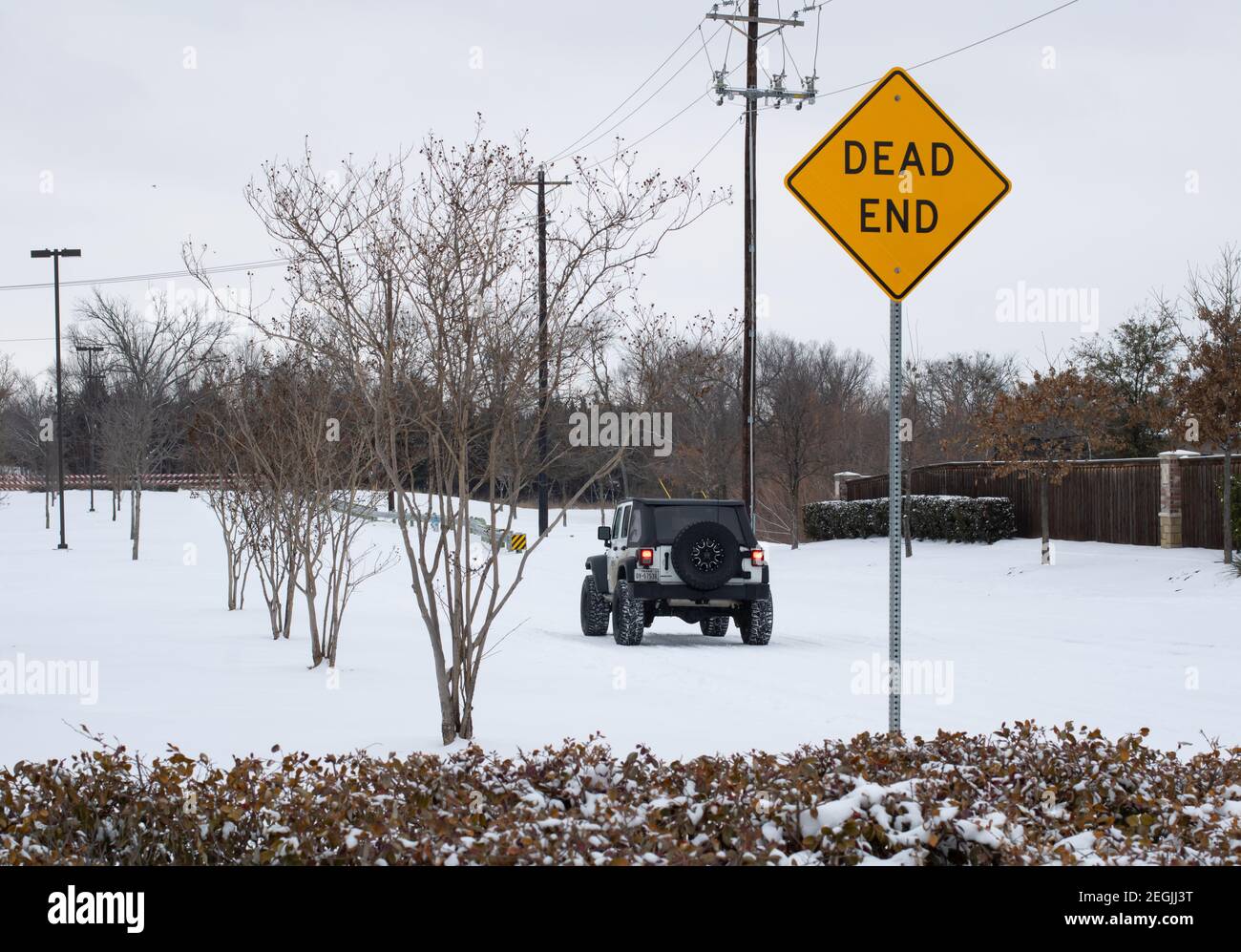 Mckinney, TX USA - February 17, 2021: Street view of Mckinney covered by heavy snow with a jeep rubicon driving on the road Stock Photo