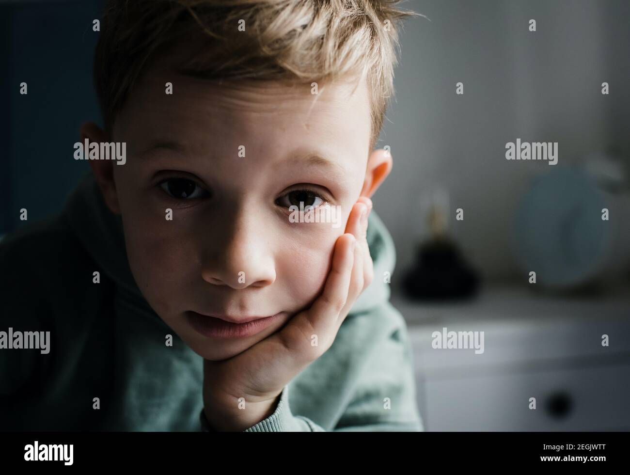 8-year-old-boy-looking-tired-thoughtful-and-expressive-at-home-stock