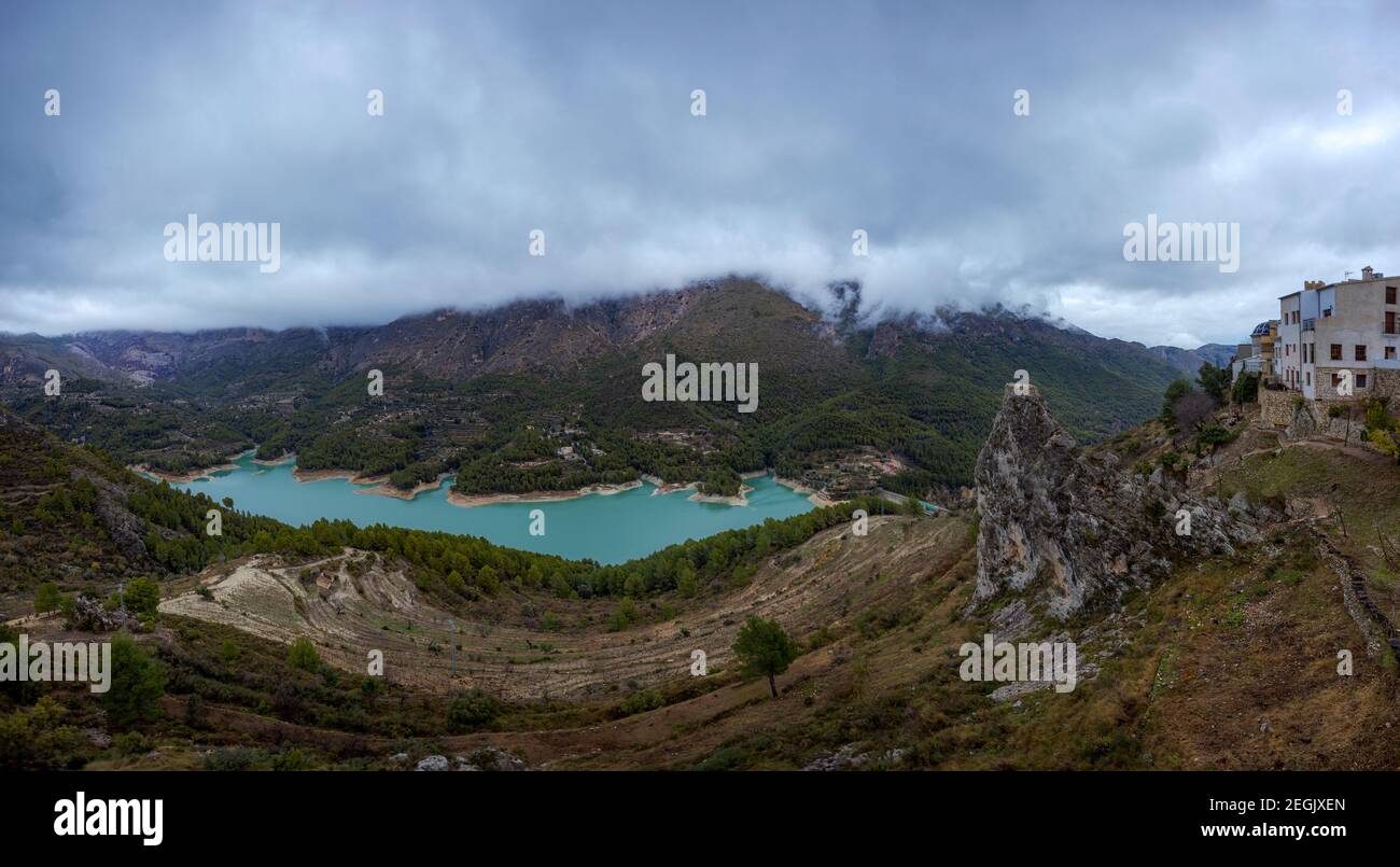 Views of lake and mountains with fog on the peaks. Gran Panoramic photo of the reservoir and city of Guadalest, Alicante, Spain. Stock Photo
