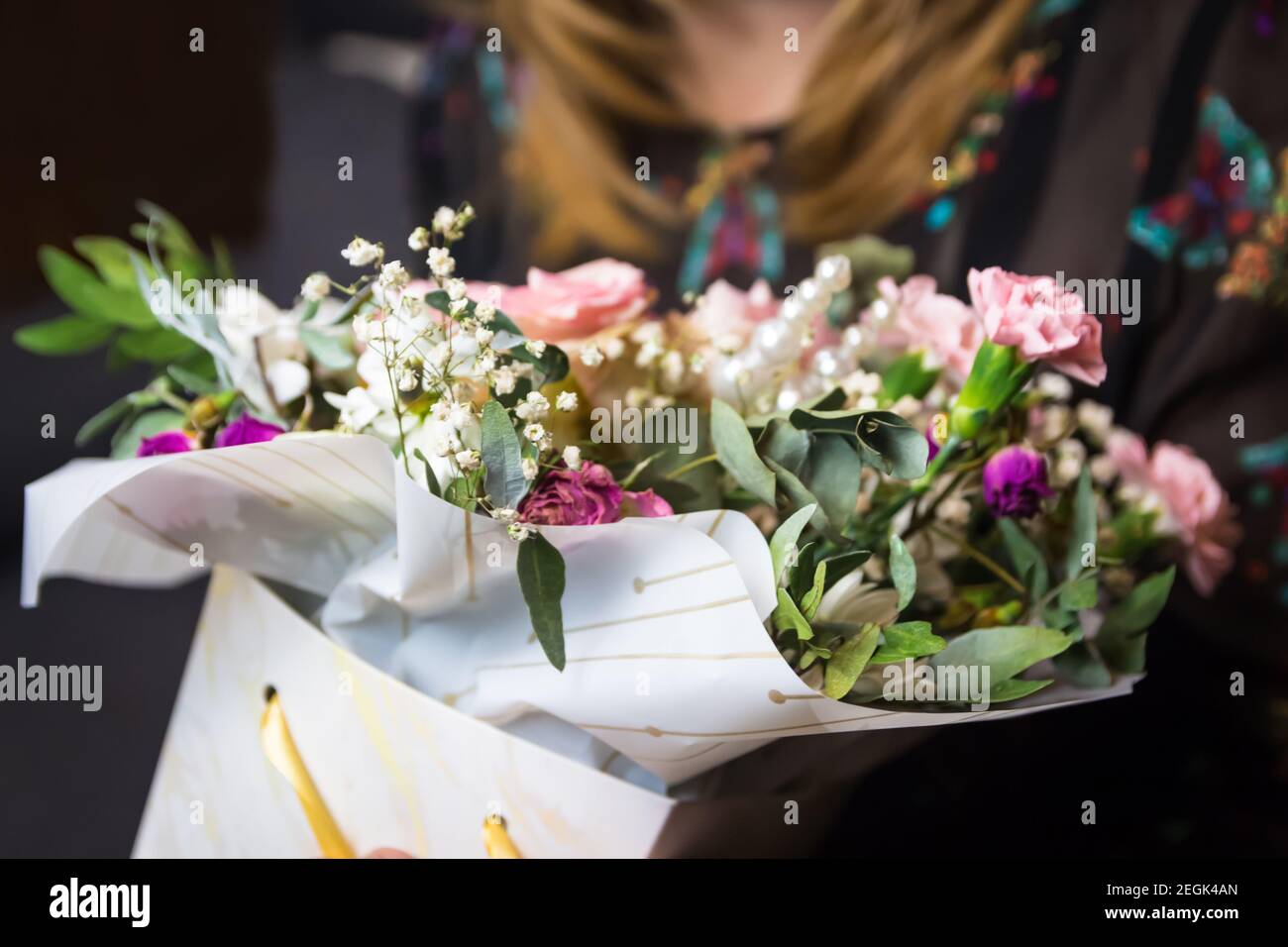 Florist woman holding a beautiful blossoming flowers bouquet in pink and green colors of roses, peony, myrtle, pistachio leaves. Woman get present Stock Photo