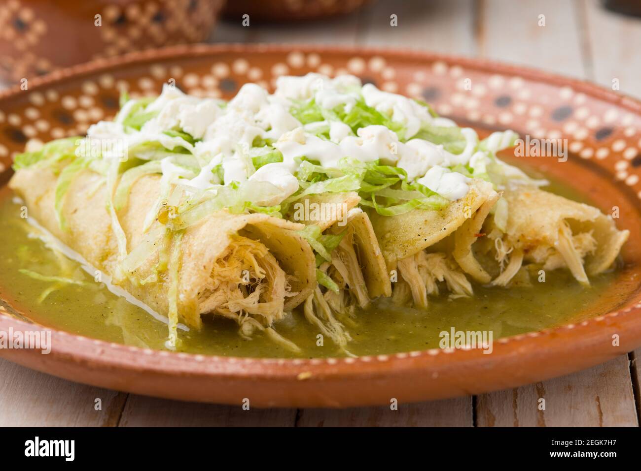 Mexican green chicken enchiladas served on a traditional clay plate Stock Photo