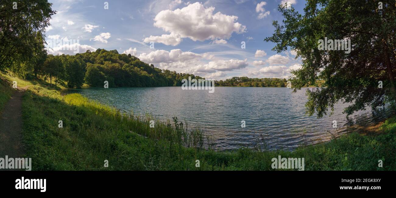 Panorama view of Weinfelder Maar at sunny summer day with blue cloudy sky, Daun, Germany Stock Photo