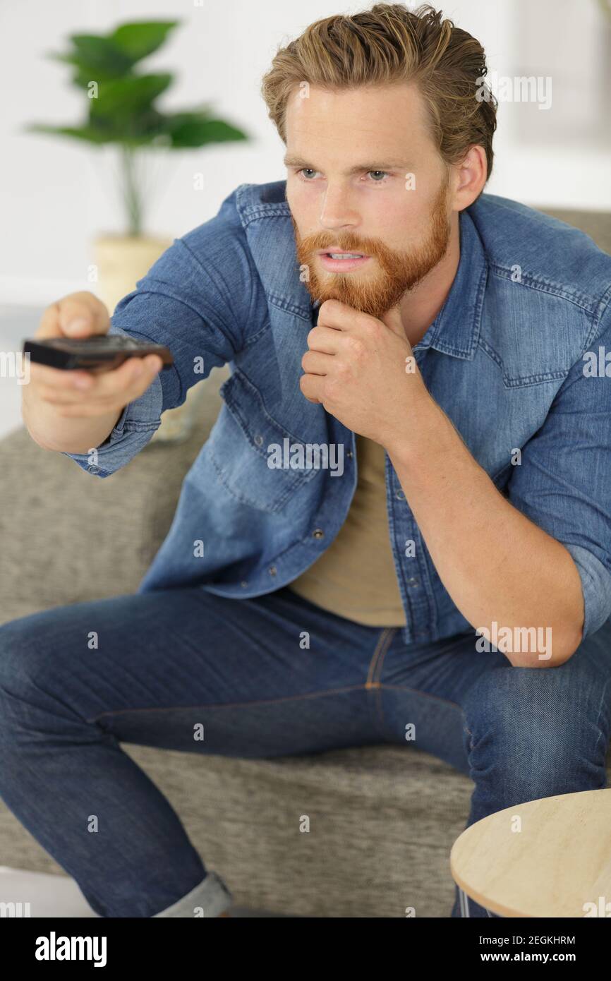 man changes the channels on the remote control Stock Photo