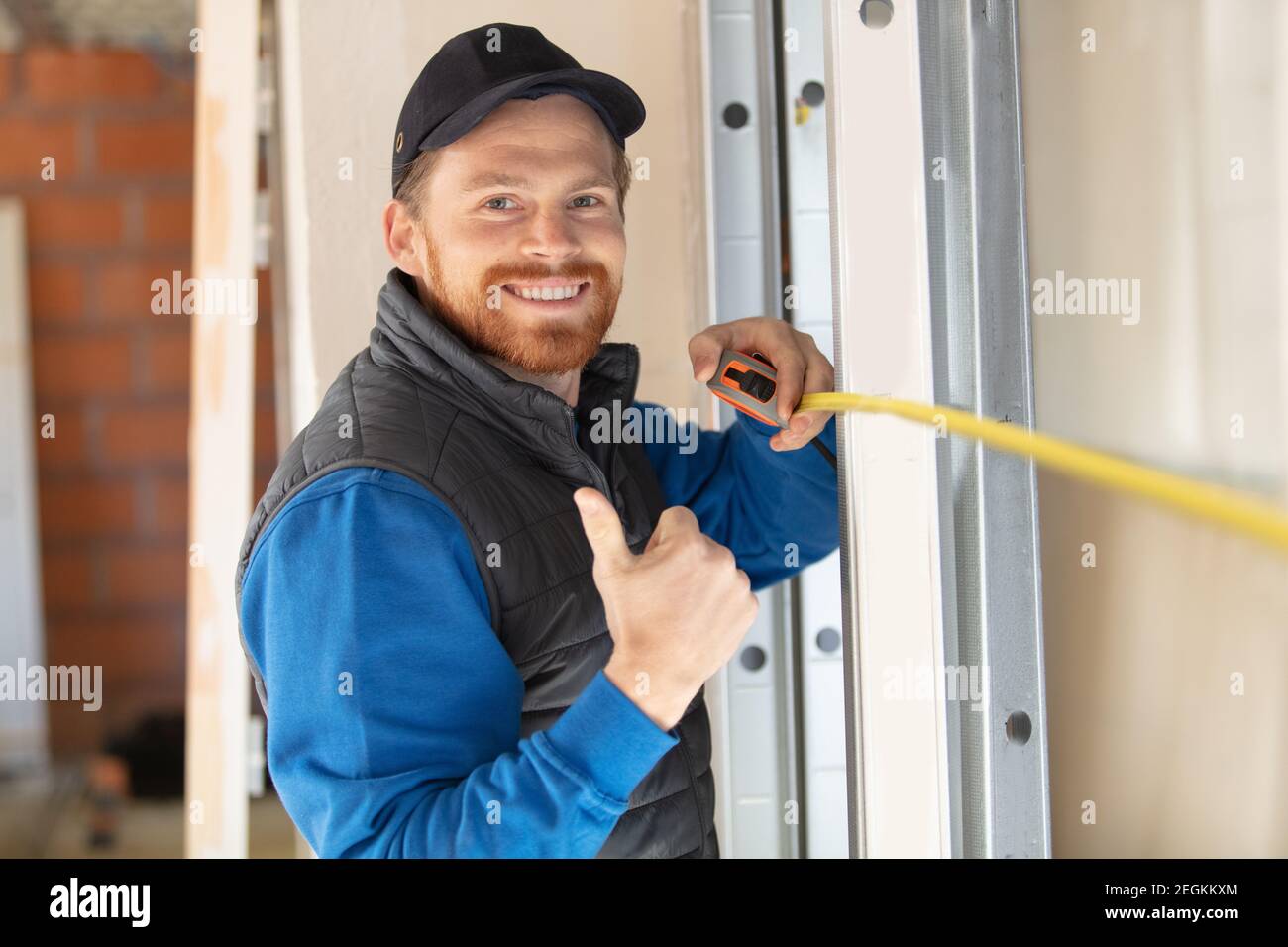 handsome builder is holding tape-measure and showing thumb-up Stock Photo