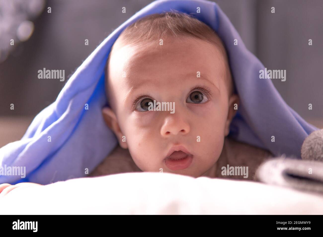 Sixmonthold baby with a blue blanket over her head Stock Photo Alamy
