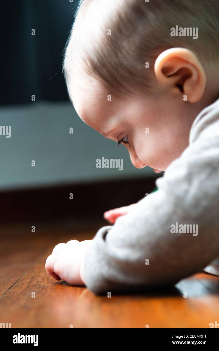sixmonthold baby in profile looking at his hands Stock Photo Alamy