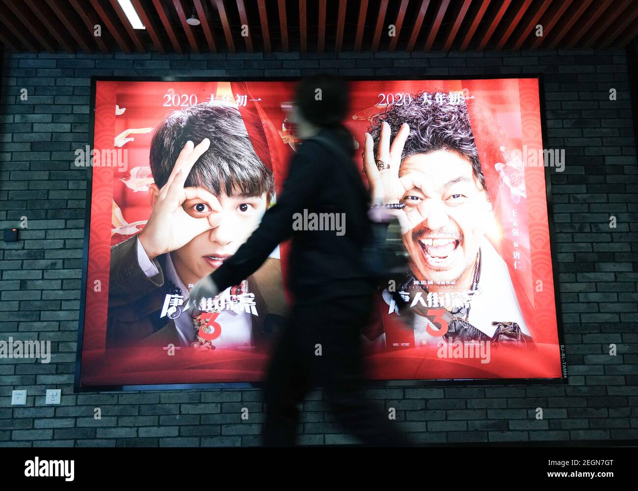 Beijing, China. 17th Feb, 2021. A pedestrian walks by a poster of movie  "Detective Chinatown 3" in Beijing, capital of China, Feb. 17, 2021. The  Spring Festival box office on the Chinese