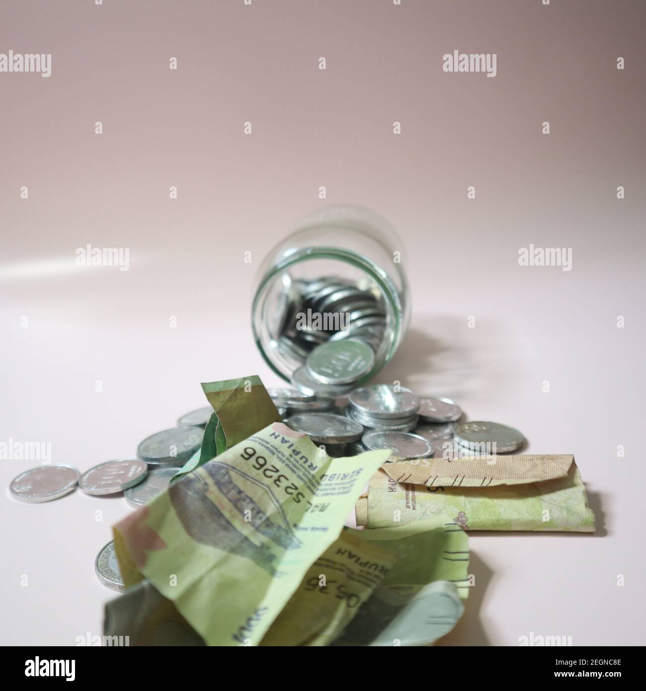 Coin Spilling from Glass Jar Stock Photo