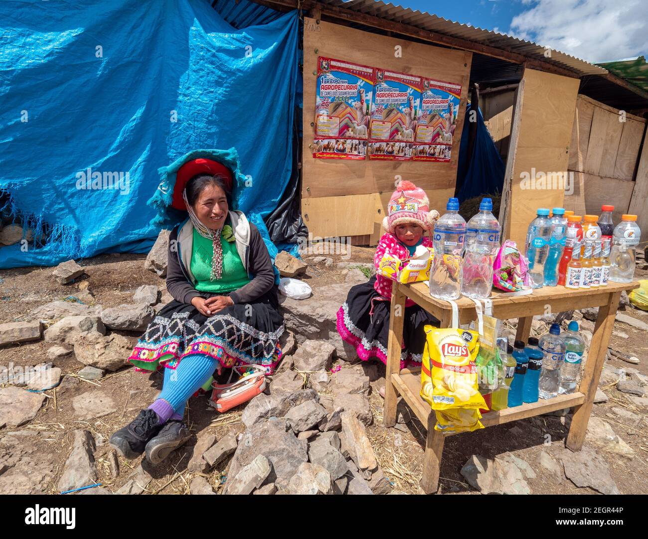 Peru, Vinicunca - October 1, 2019 - Indian woman dressed in traditional clothes sells products at store with small daughter Stock Photo