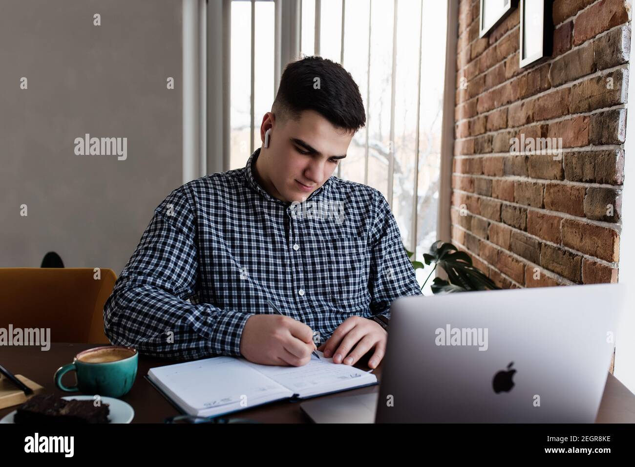 Man working at the laptop with a cup of coffee at home. Blurred background Stock Photo