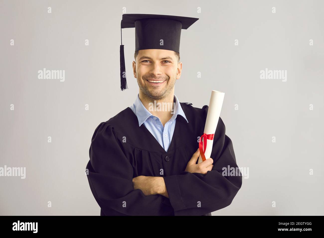 Studio portrait of happy university graduate holding his diploma and smiling at camera Stock Photo