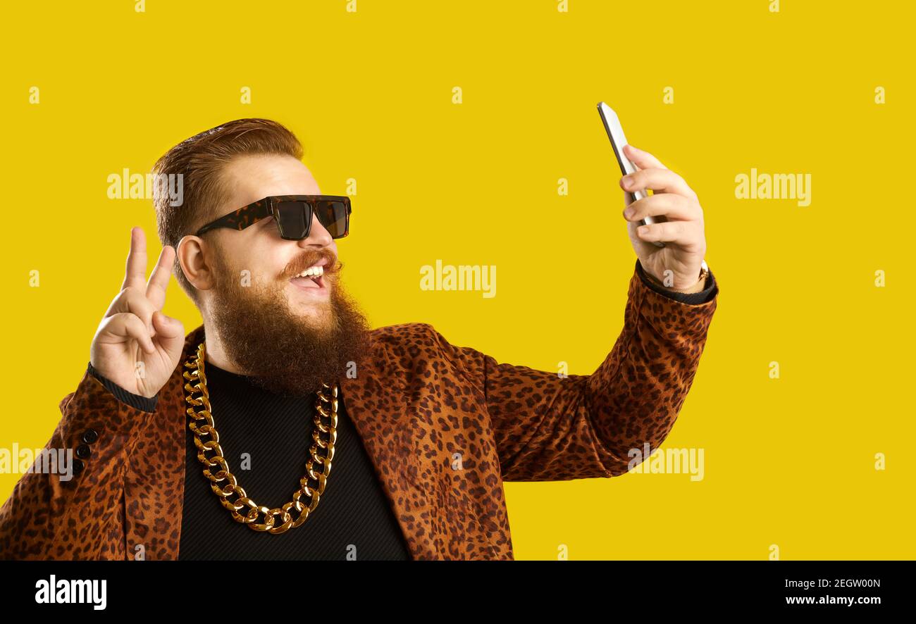 Happy man in an extravagant outfit taking a selfie or live streaming on a smartphone Stock Photo
