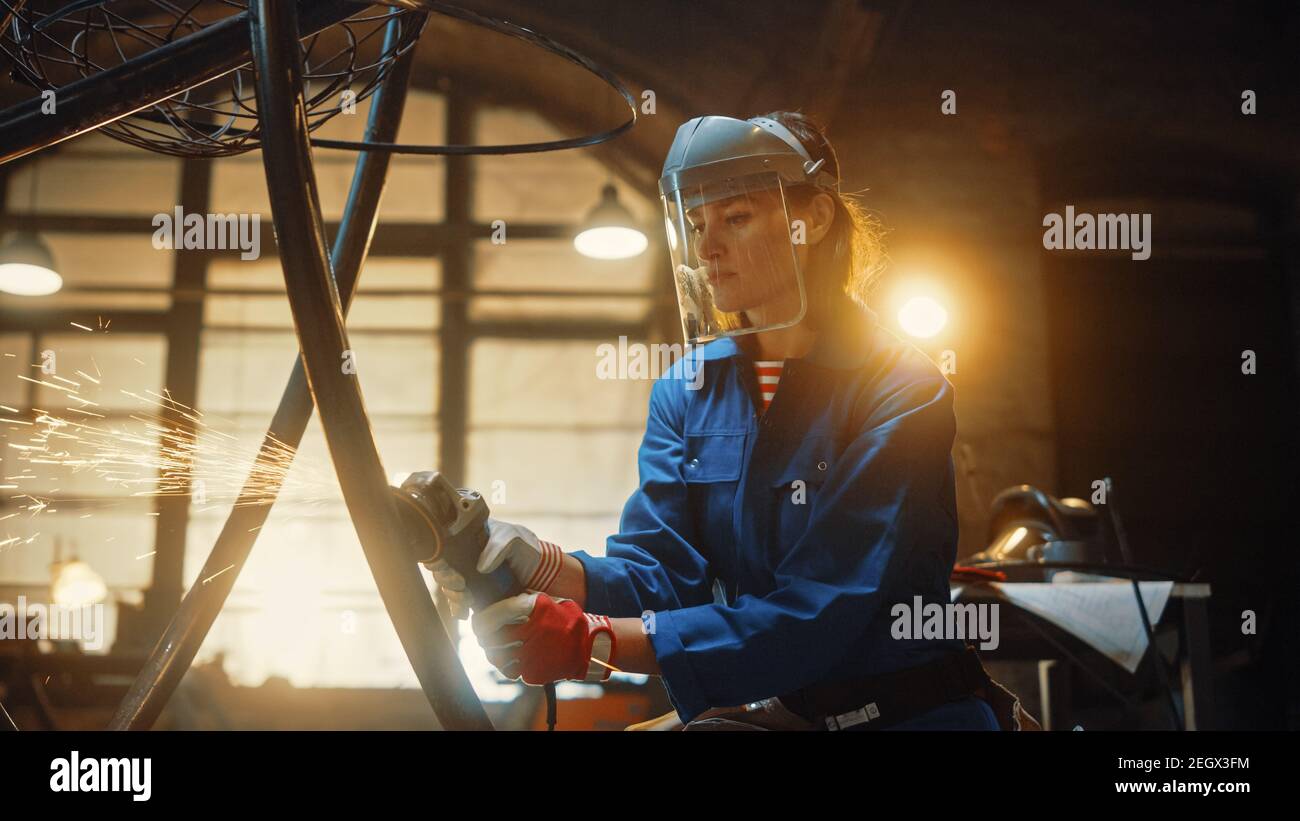 Close Up Portrait of Beautiful Female Fabricator in Safety Mask. She is Grinding a Metal Object and Flying Hot Sparks Reflect on the Mask. Empowering Stock Photo