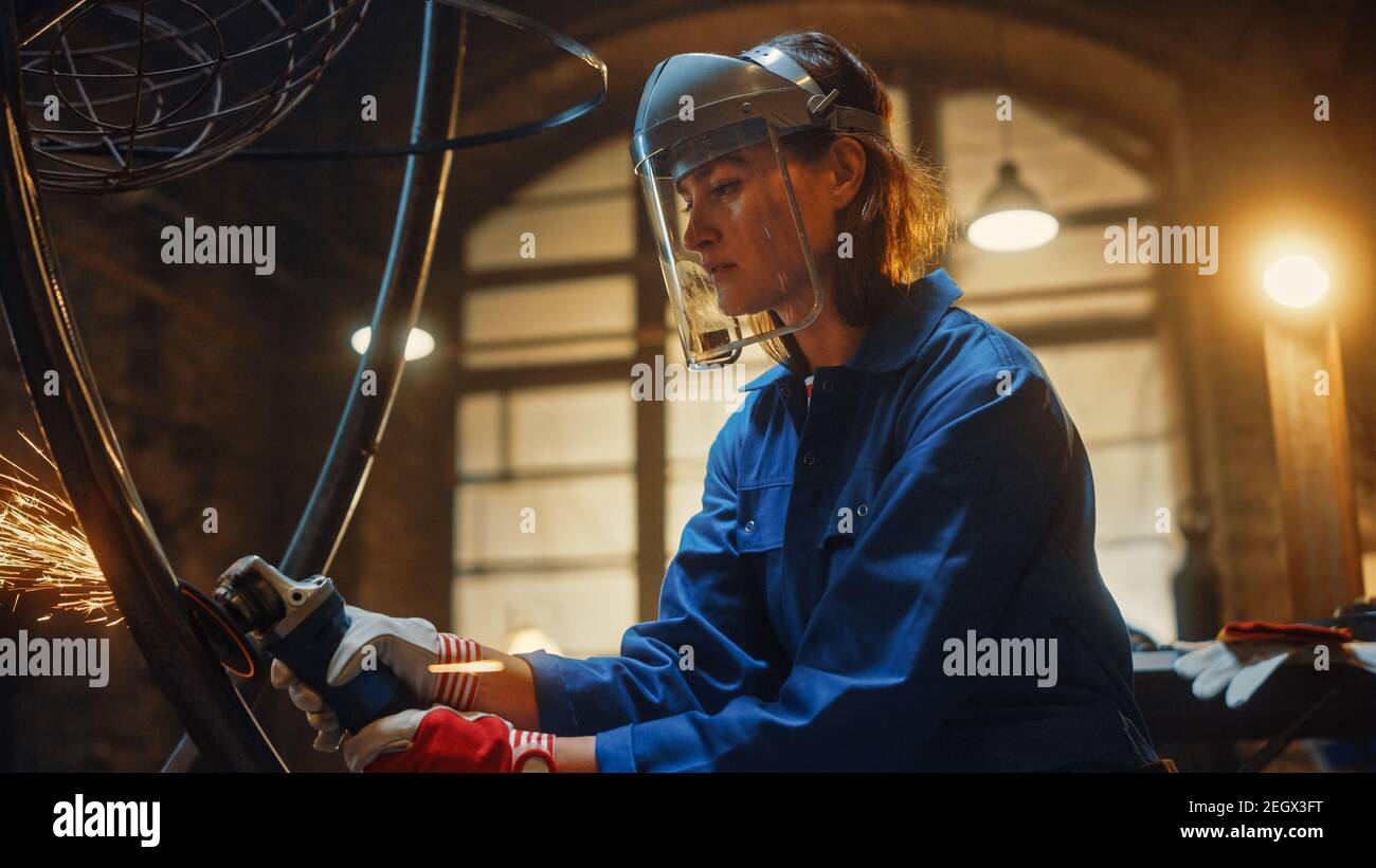 Close Up Portrait of Beautiful Female Fabricator in Safety Mask. She is Grinding a Metal Object and Flying Hot Sparks Reflect on the Mask. Empowering Stock Photo