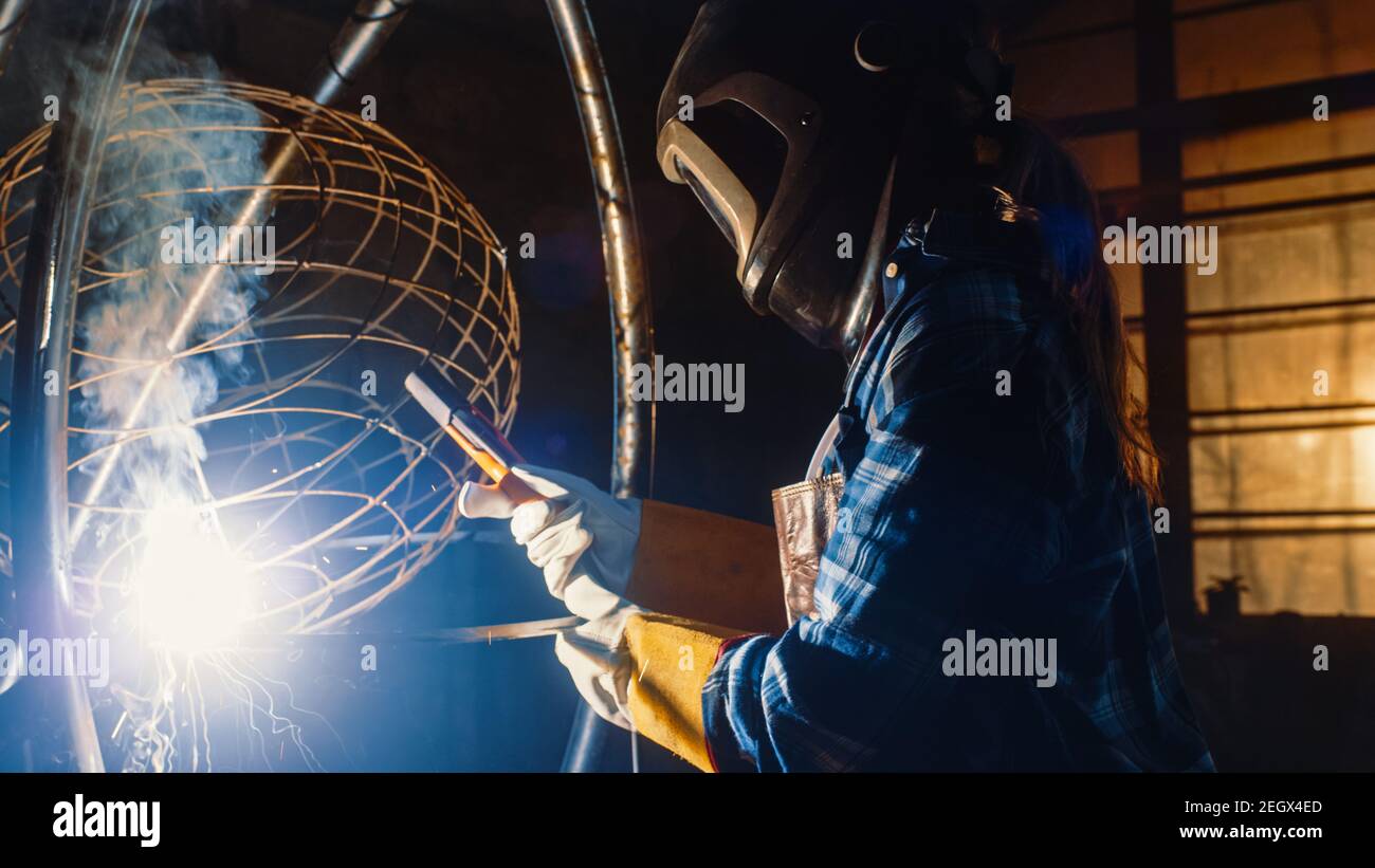 Talented Emerging Female Artist is Welding an Abstract, Brutal Metal Sculpture that Reflects the Present Moment. Beautiful Tomboy Fabricator in Stock Photo