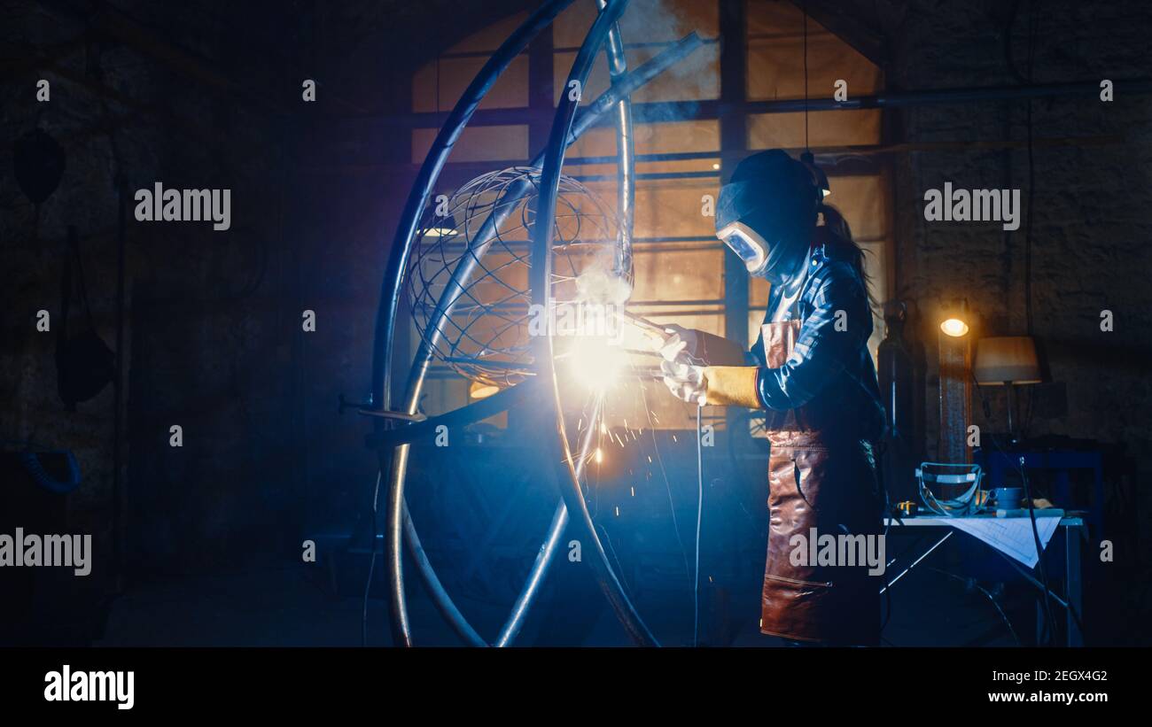 Talented Emerging Female Artist is Welding an Abstract, Brutal Metal Sculpture that Reflects the Present Moment. Beautiful Tomboy Fabricator in Stock Photo