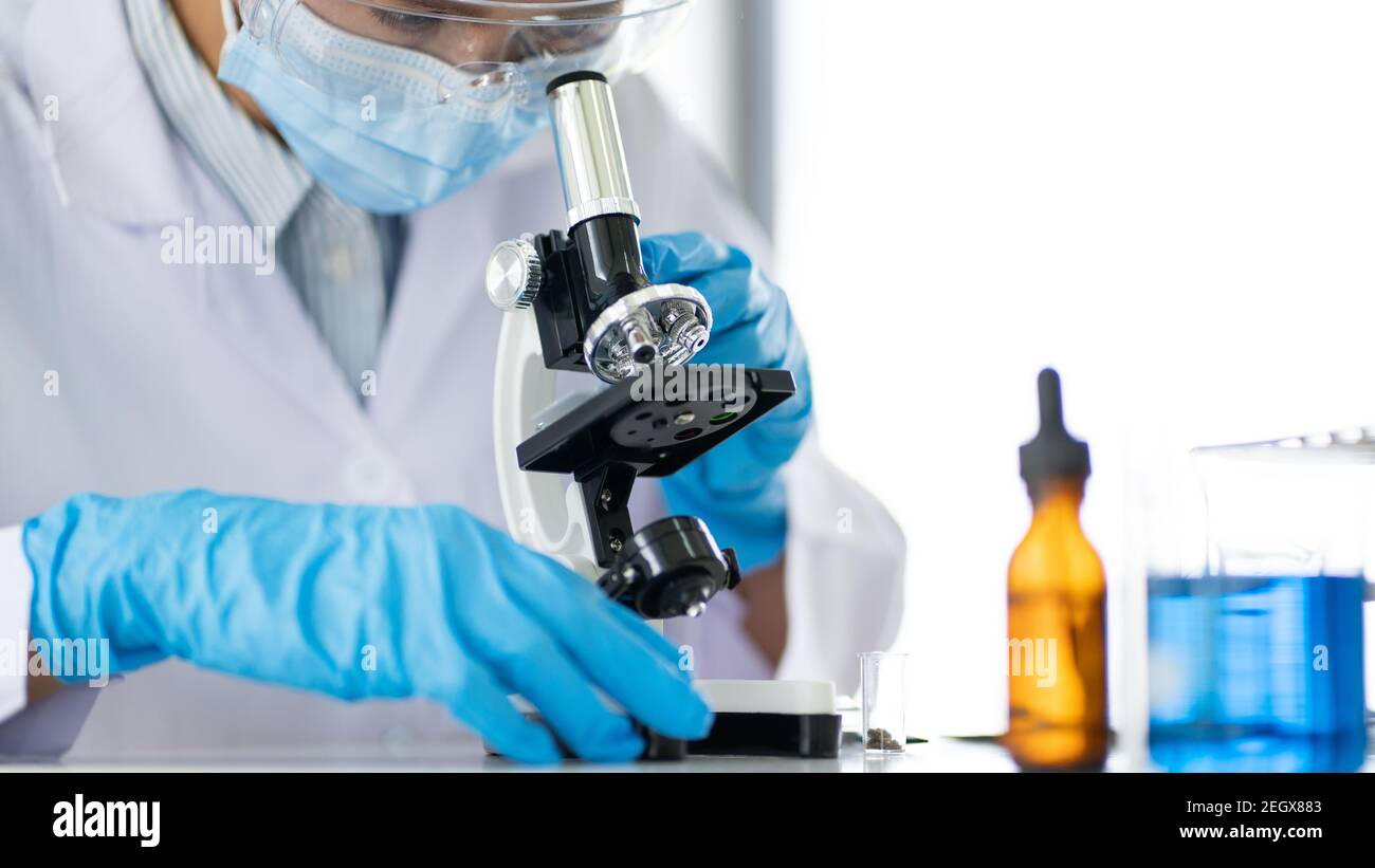 Young Asian scientist Working looking through a microscope doing ...