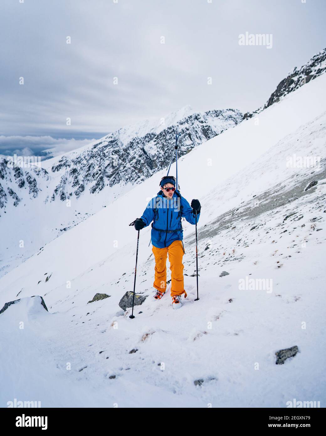 Portrait of a happy male freeride skier in the Alps. Winter extreme sport concept. Free-ride skier walking in the snow. Red jacket Stock Photo