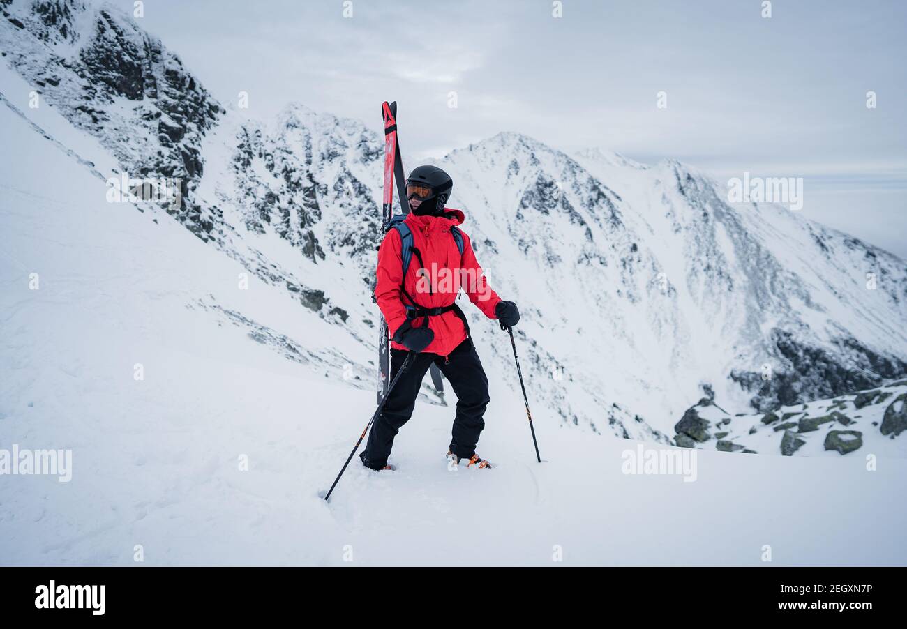 Portrait of a happy male freeride skier in the Alps. Winter extreme sport concept. Free-ride skier walking in the snow. Red jacket Stock Photo