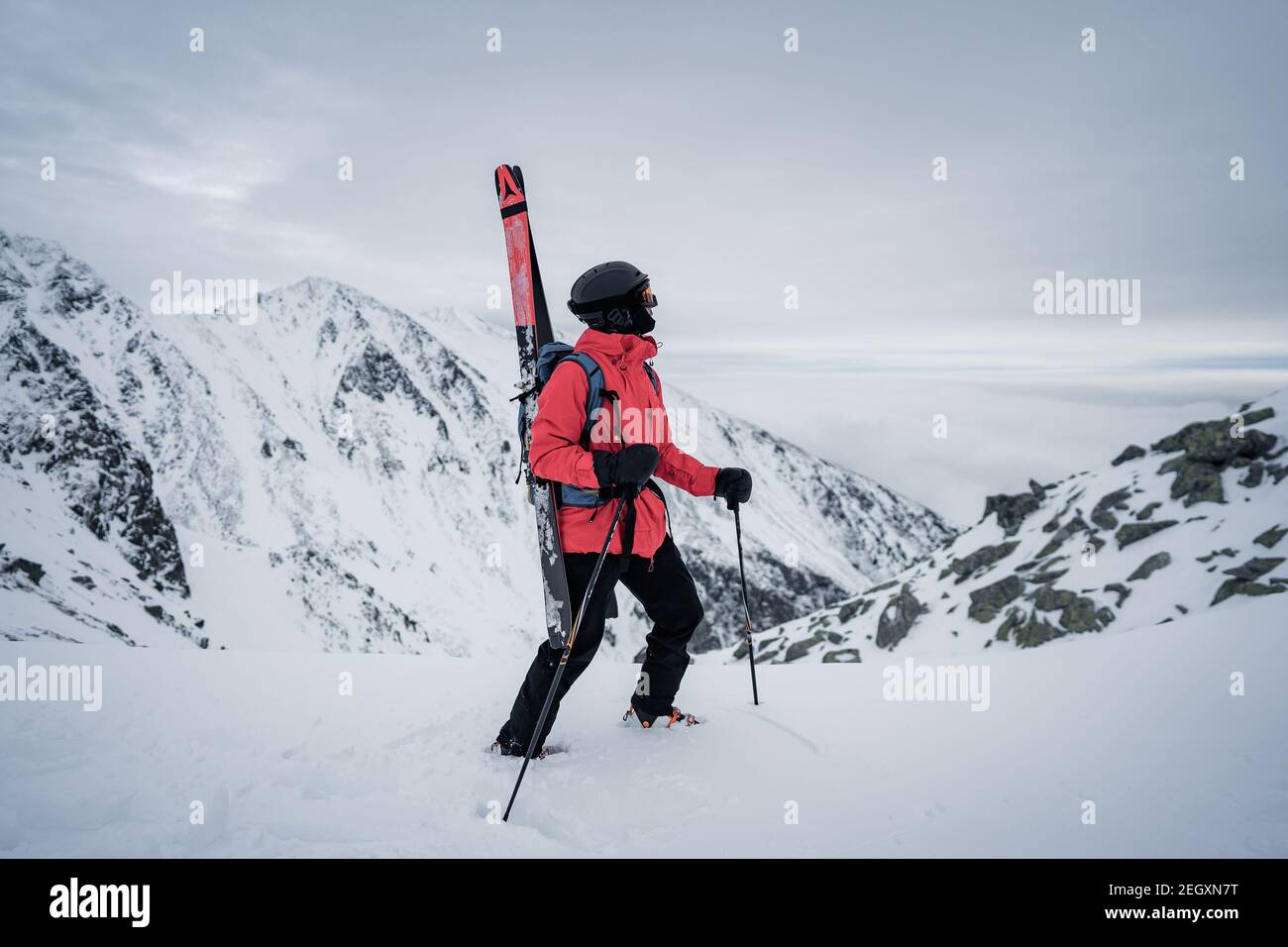 Portrait of a happy male freeride skier in the Alps. Winter extreme sport concept. Free-ride skier walking in the snow. Red jacket Stock Photo